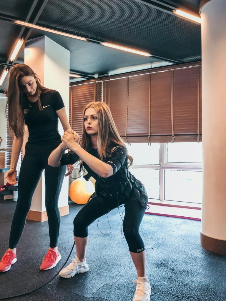 Coach sportive accompagnant une cliente en salle de sport